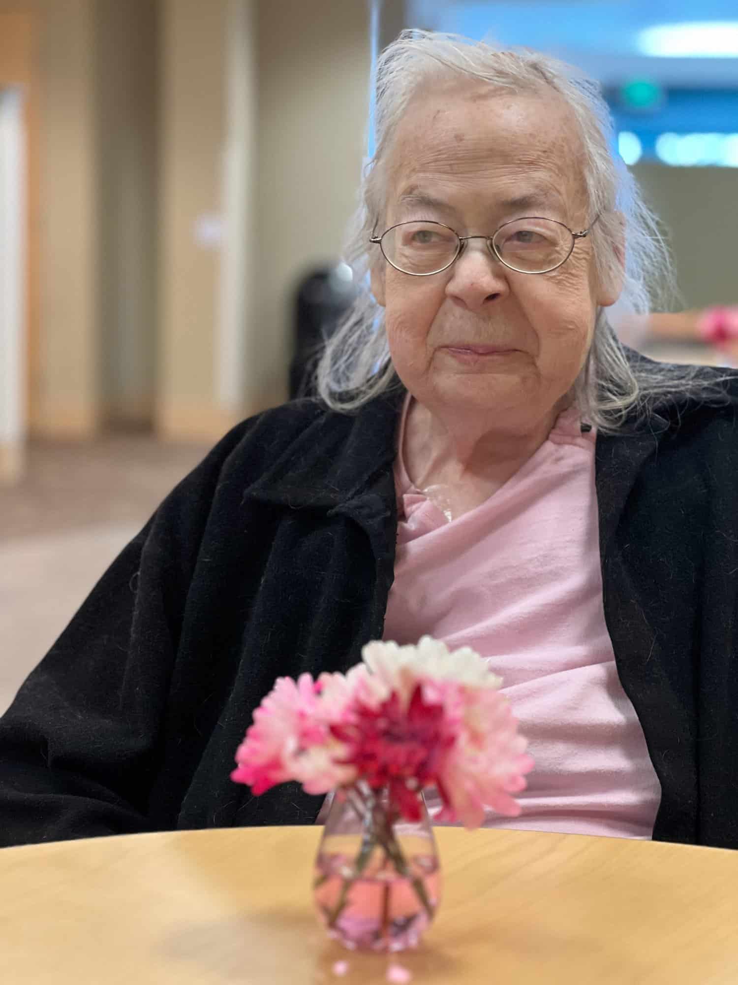 Susan Robbins sitting at a table with a small bouquet of flowers in front of her