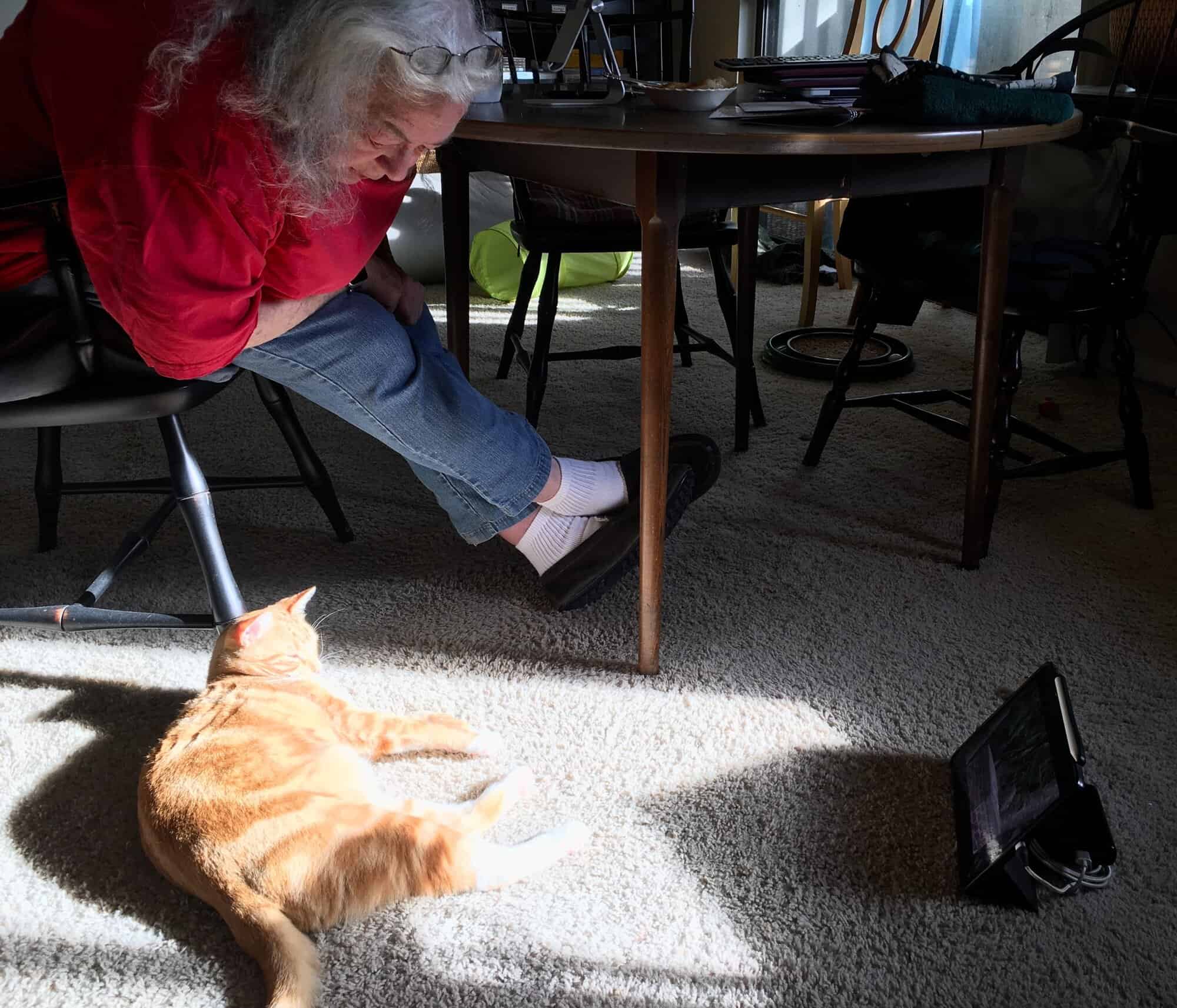Susan leaning over to watch Butters lying next to the floor beside her
