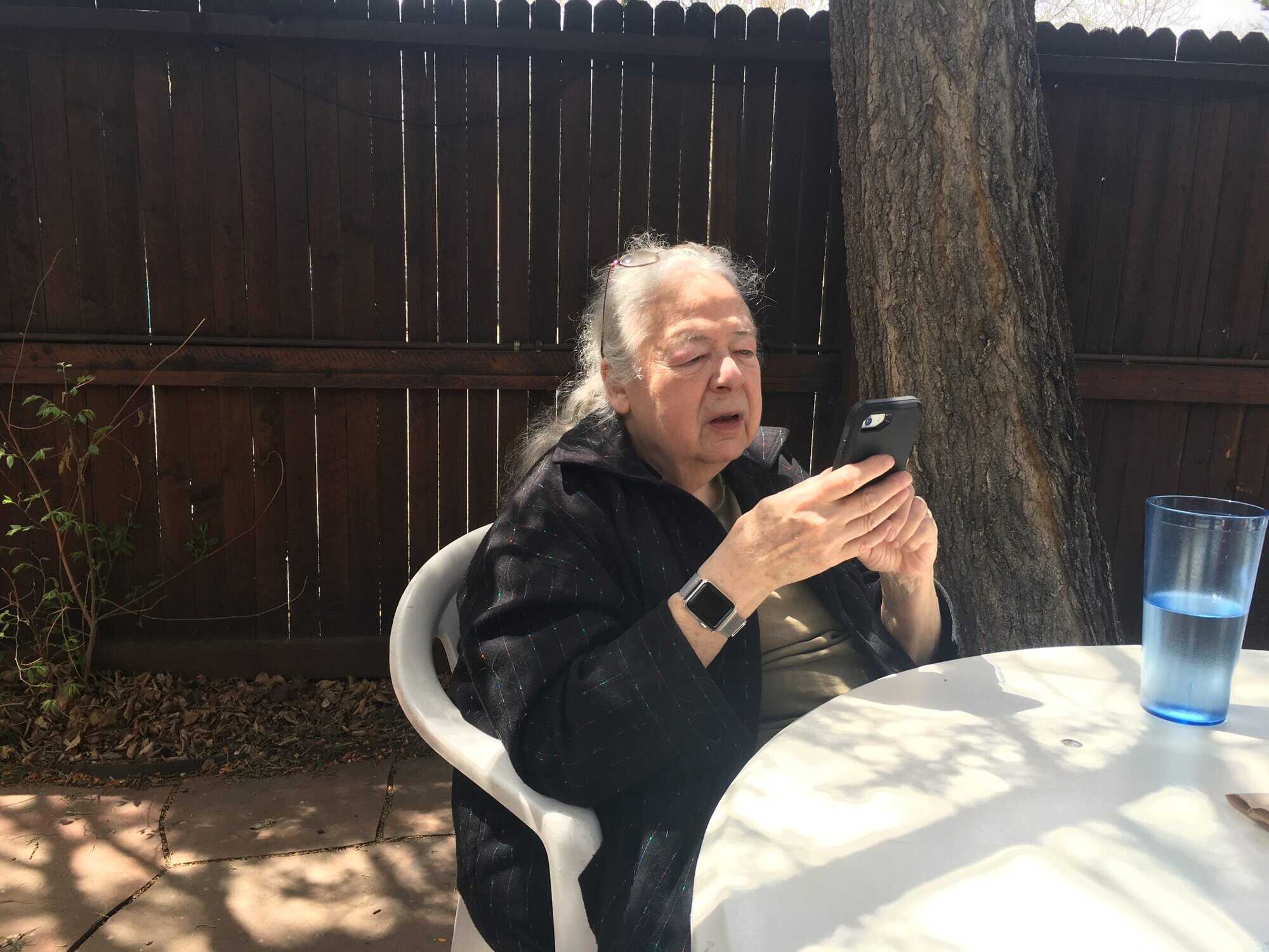 Susan at an outdoor restaurant table looking at her phone