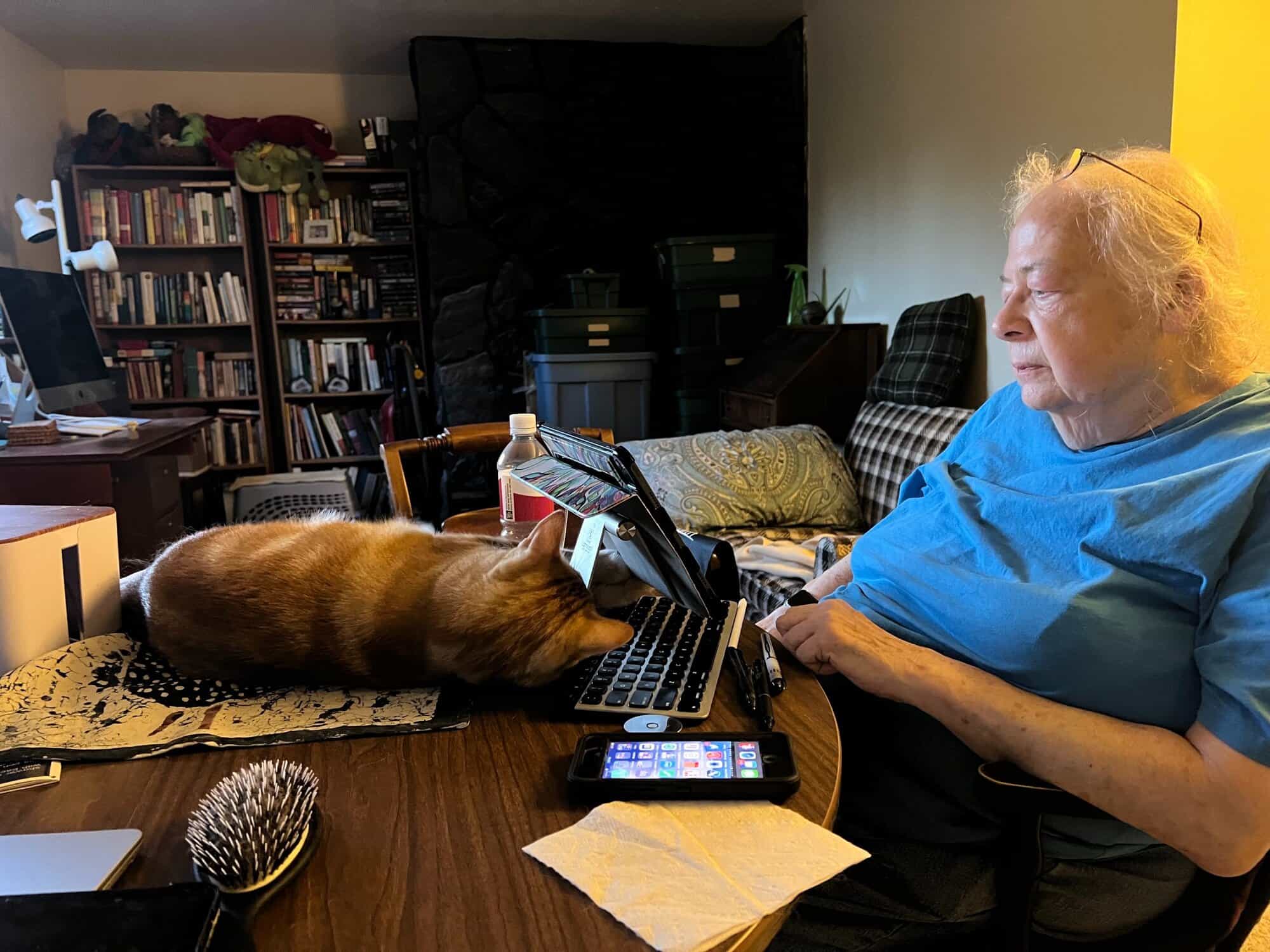 Susan looking at Butters, who is lying behind her tablet on the table in front of her