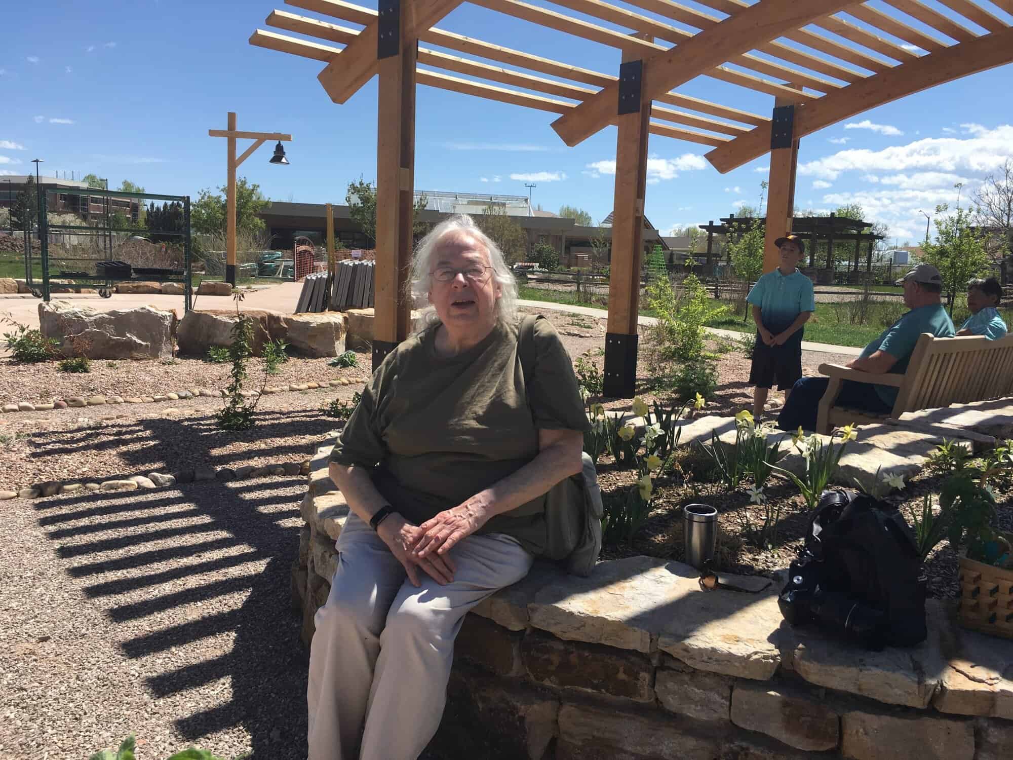 Susan sitting under a pergola at The Gardens on Spring Creek
