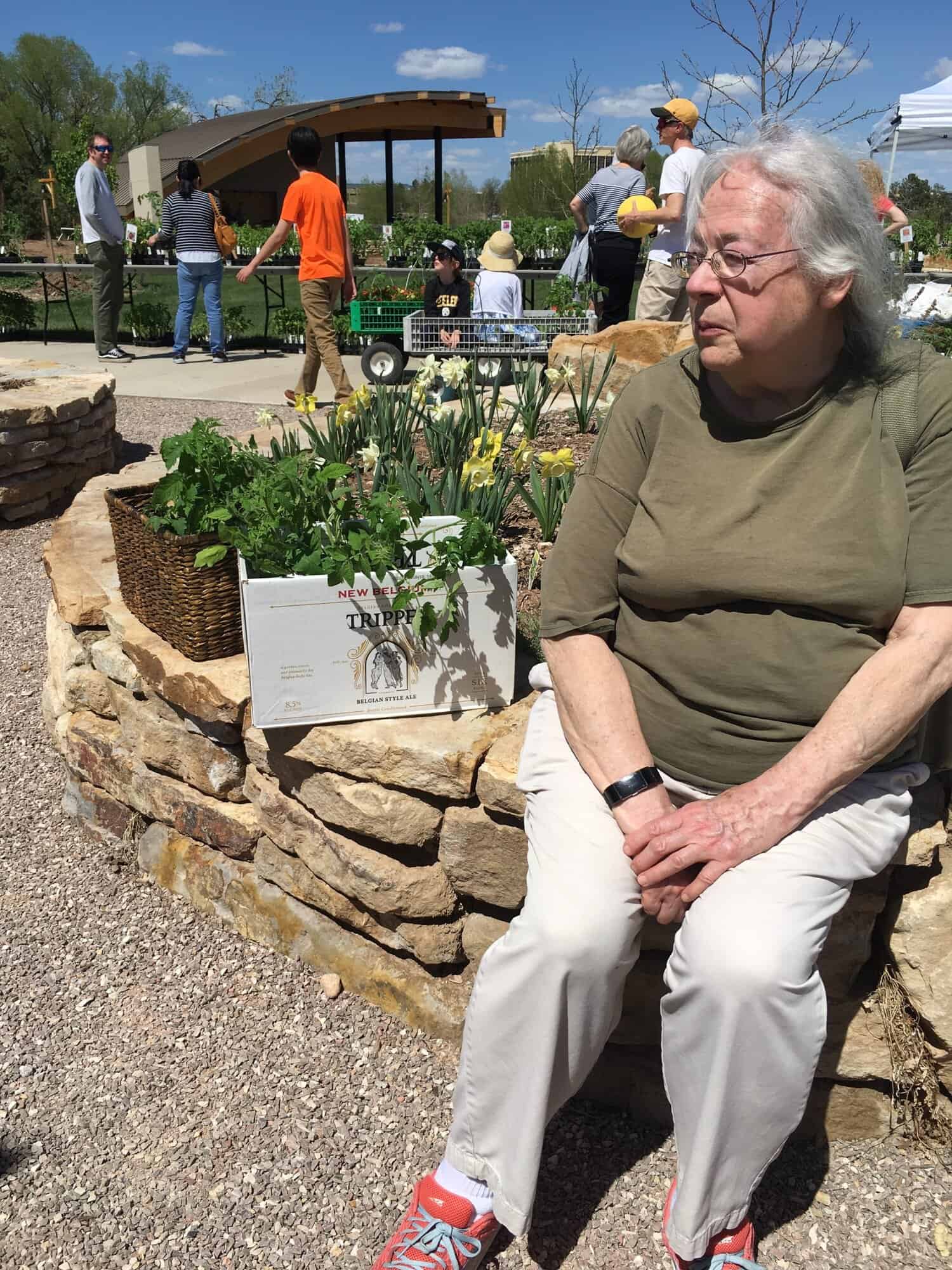 Susan sitting on a low stone wall at The Gardens on Spring Creek