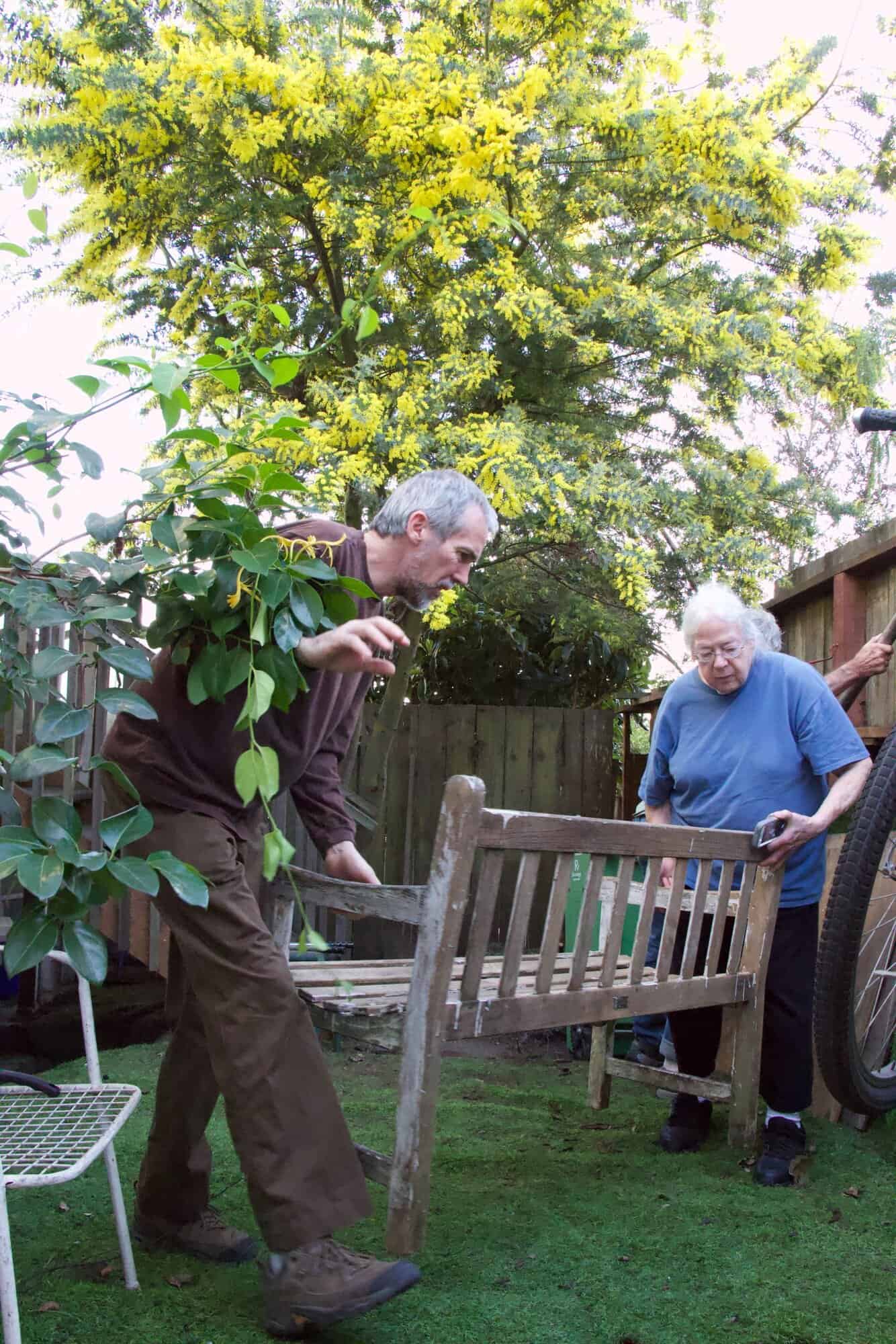Steve and Susan moving a bench in a leafy San Francisco back yard