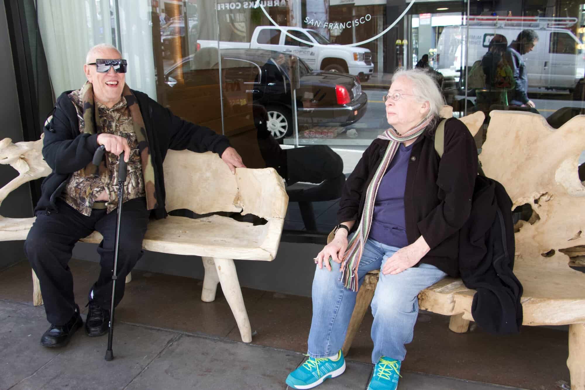 Jet and Susan sitting on benches in front of a San Francisco store